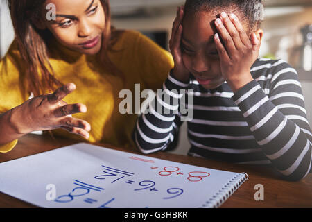 Mother learning child to calculate, child looking frustrated. Black woman and child Stock Photo