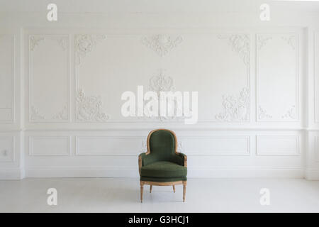 Living room with antique stylish green armchair on luxury white wall design bas-relief stucco mouldings roccoco elements Stock Photo