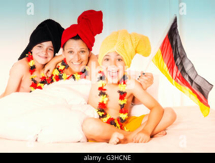 mother and two sons with german flag sitting in bed and cheering Stock Photo