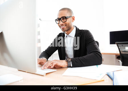 Smiling smart businessman working with computer at the office Stock Photo