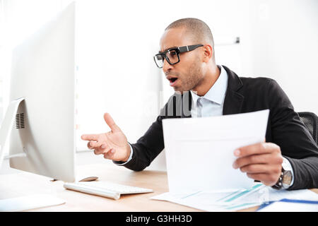 Young smart businessman using a laptop and looking shocked Stock Photo