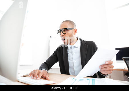 Young smart businessman using a laptop and looking shocked Stock Photo