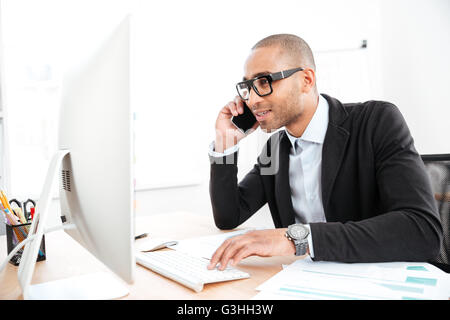Office worker calling on the phone and reading business document in the office Stock Photo