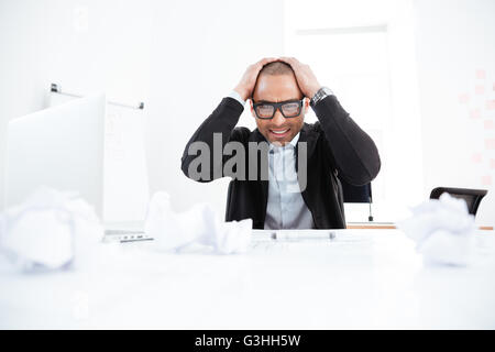 Overworked stressed businessman working on laptop computer and having headache Stock Photo