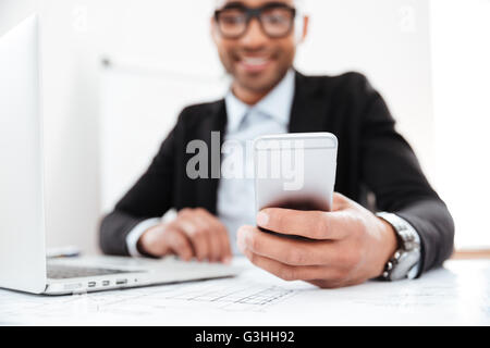 Happy young businessman using mobile phone while working in the office Stock Photo