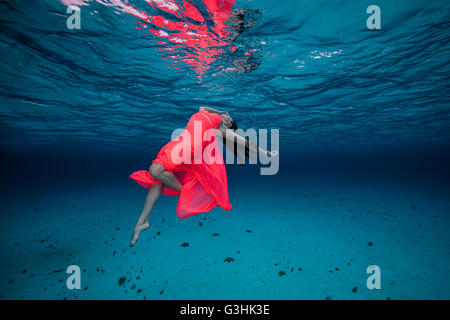 Woman underwater in red dress Stock Photo