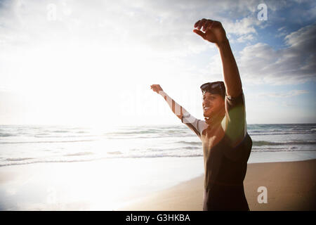 Diver raising arms on beach Stock Photo
