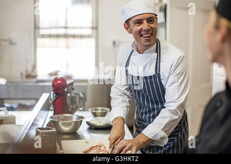 Chefs chatting and preparing food in kitchen Stock Photo