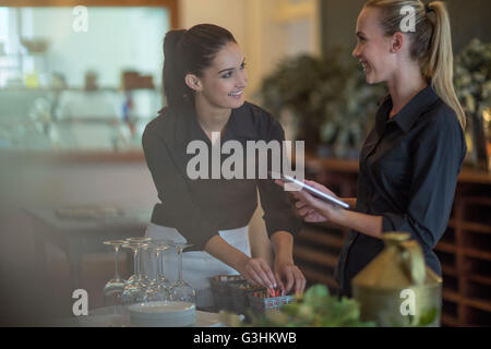 Waitresses chatting and setting table in restaurant Stock Photo