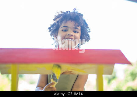 Young boy painting wooden birdhouse Stock Photo