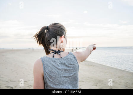 Young woman pointing toward horizon from beach, Tamarindo, Guanacaste, Costa Rica Stock Photo