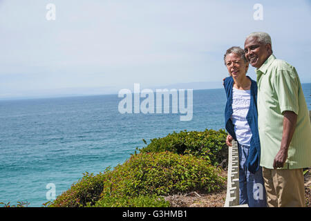 Senior couple standing outside, near ocean, looking at view Stock Photo