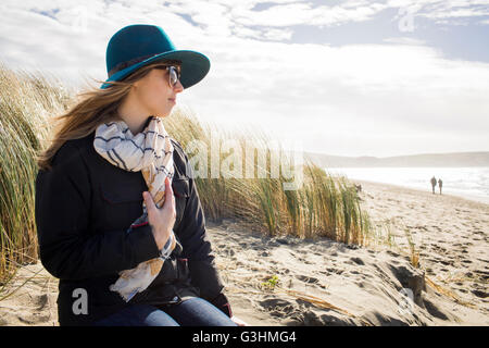 Woman wearing felt hat and sunglasses looking out from dunes, Dillon Beach, California, USA Stock Photo