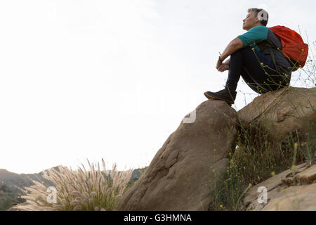Woman hiker sitting on top of rocks looking away Stock Photo