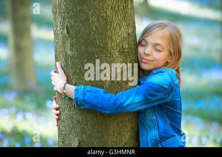 Girl hugging tree in bluebell forest, Hallerbos, Brussels, Belgium Stock Photo