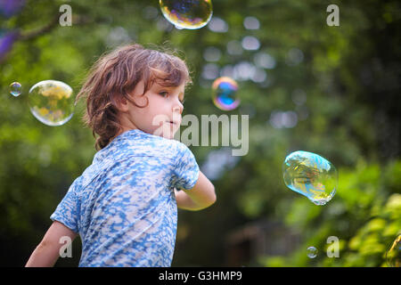 Girl waving bubble wand in garden Stock Photo