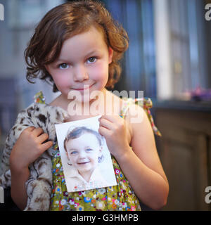 Portrait of girl holding photograph of herself Stock Photo