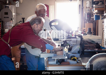 Senior men sawing woodblock on circular saw in carpentry workshop Stock Photo