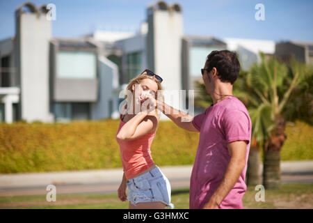 Couple outdoors, holding hands, woman kissing man's hand Stock Photo