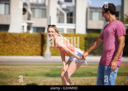 Couple fooling around outdoors, holding hands, laughing Stock Photo