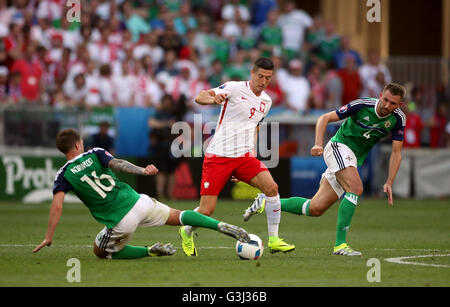 Poland's Robert Lewandowski battles for the ball with Northern Ireland's Oliver Norwood (left) and Gareth McAuley (right) during the UEFA Euro 2016, Group C match at the Stade de Nice, Nice. Stock Photo