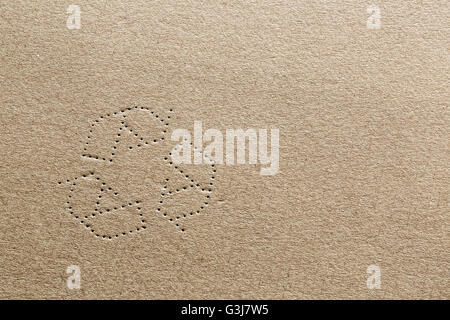 Highly detailed photograph of cardboard with the shape of the recycling symbol punched into the carton material. Stock Photo