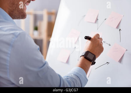 Positive smiling man making notes on the board Stock Photo
