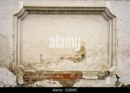 Recessed architectural detail of a grunge window style brickwork on a white wall with crumbling paintwork and cracked plaster Stock Photo
