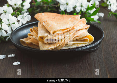 Homemade crepes  folded in triangles on frying pan on spring blossom background Stock Photo