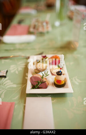 A small plate of appetizers on a green table at a wedding reception with a blank name card in front. Stock Photo