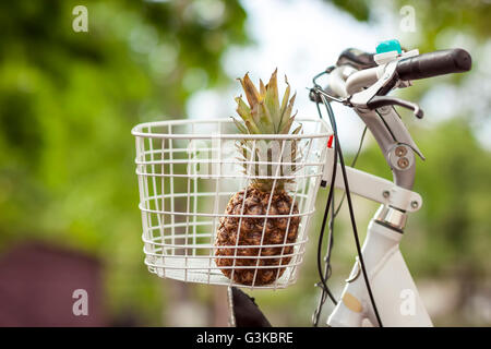 Pineapple in bike basket green blurred background bokeh Stock Photo
