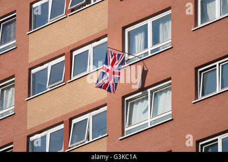 A Union Jack hanging from a window in a block of flats. Stock Photo