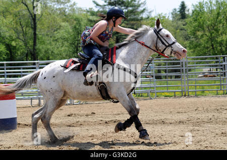 Teenage girl galloping past a barrel during a barrel race Stock Photo