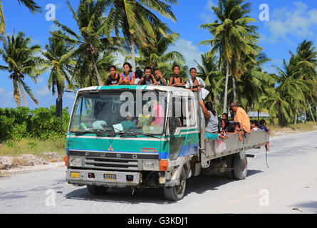 Local children hitching a ride home from school, Christmas Island, Kiribati Stock Photo