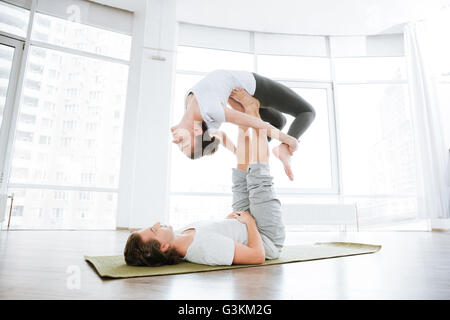 Peaceful couple doing acro yoga exercises in studio together Stock Photo