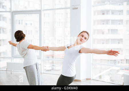 Beautiful young woman practicing yoga with partner in studio Stock Photo
