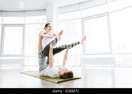 Smiling couple practicing acro yoga exercises in studio together Stock Photo