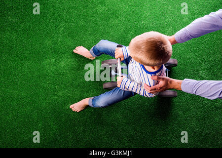 Unrecognizable father holding his son riding a bike Stock Photo