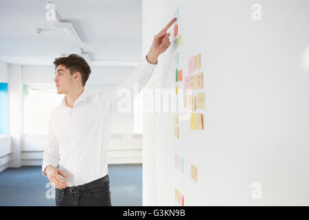 Man giving presentation pointing at adhesive notes on wall Stock Photo