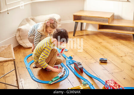 Young girl and boy playing with toy train set Stock Photo