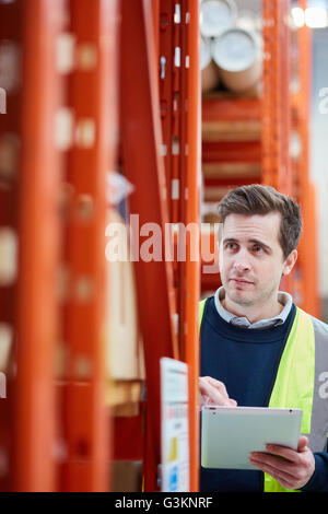 Male factory worker using digital tablet in factory warehouse Stock Photo