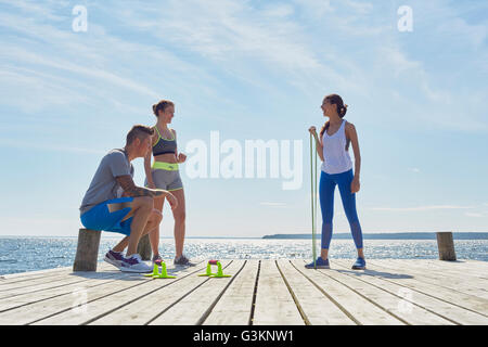 Friends wearing sports clothes on pier with exercise equipment Stock Photo