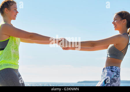 Women wearing sports clothes face to face holding hands smiling Stock Photo