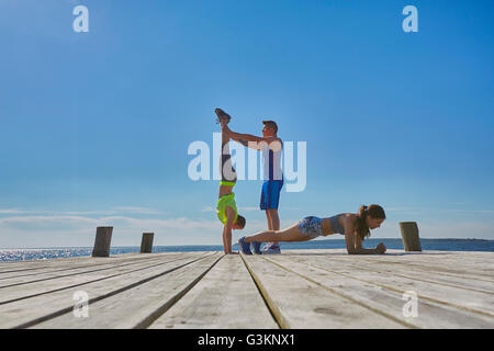 Friends on pier doing handstands and push ups Stock Photo