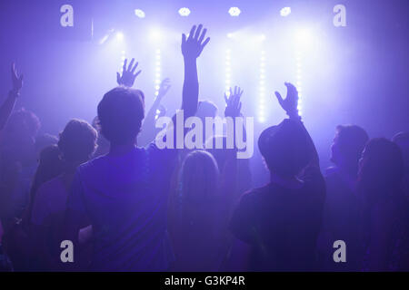 Rear view of group in club arms raised watching concert Stock Photo