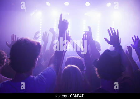 Rear view of group in club arms raised watching concert Stock Photo