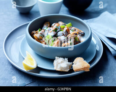 Mussels, leeks, sauce and herbs in bowl with lemon slice Stock Photo