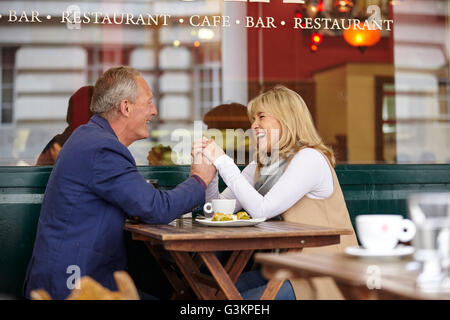 Mature dating couple holding hands at sidewalk cafe table Stock Photo