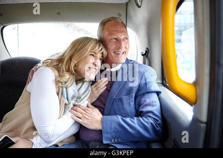 Mature romantic dating couple en route in black cab backseat Stock Photo