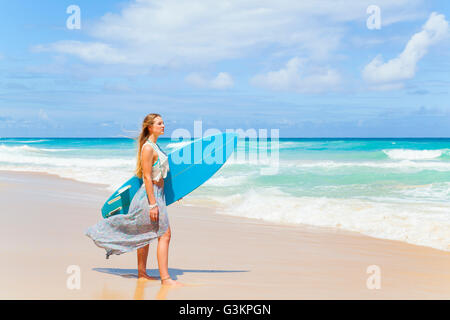 Young woman carrying surfboard on beach, Dominican Republic, The Caribbean Stock Photo